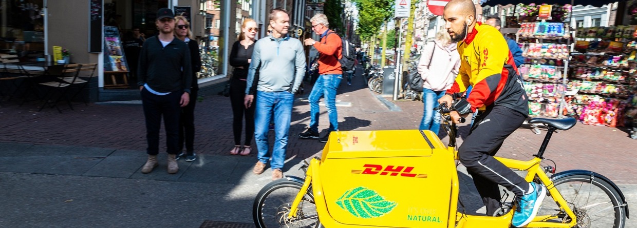 Jonge mens op leveringsfiets die in Amsterdam, Nederland circuleert, schade zakelijk, e-bike, verzekeringen, zakelijke e-bike
